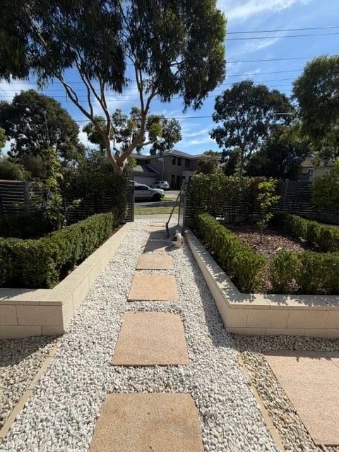 Paved garden path with white pebbles and clipped border planting
